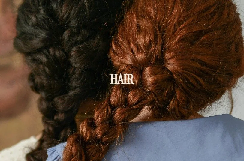 Two women with braided hair, one with dark brown hair and the other with red hair, seen from behind. The word "HAIR" appears over the red hair.