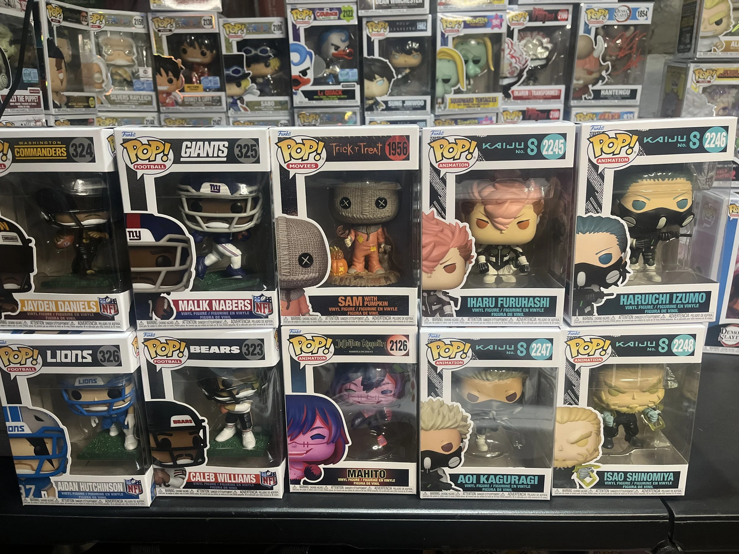 Display of various Funko Pop! vinyl figures in boxes on store shelves, including characters from NFL, Giants, movies, anime, and popular series.