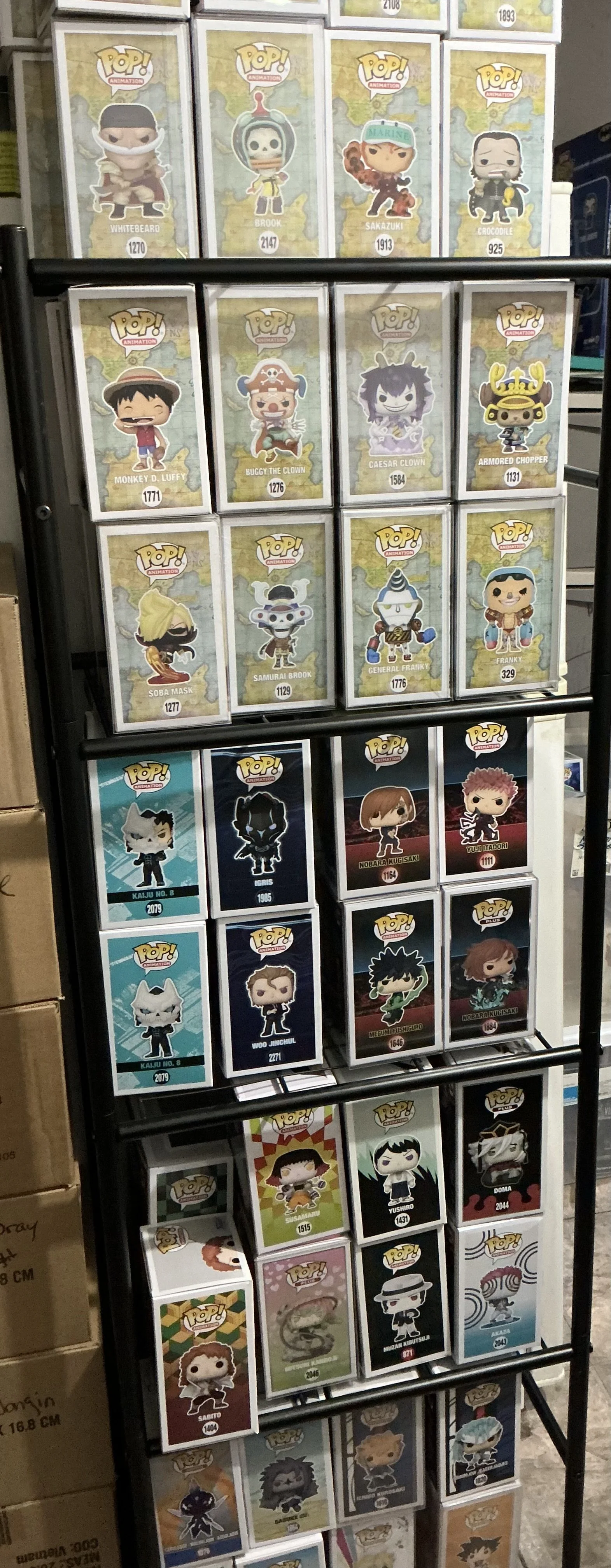 Shelf of Funko Pop! figures, mostly featuring characters from anime, video games, and pop culture, in boxes with their names and numbers visible.