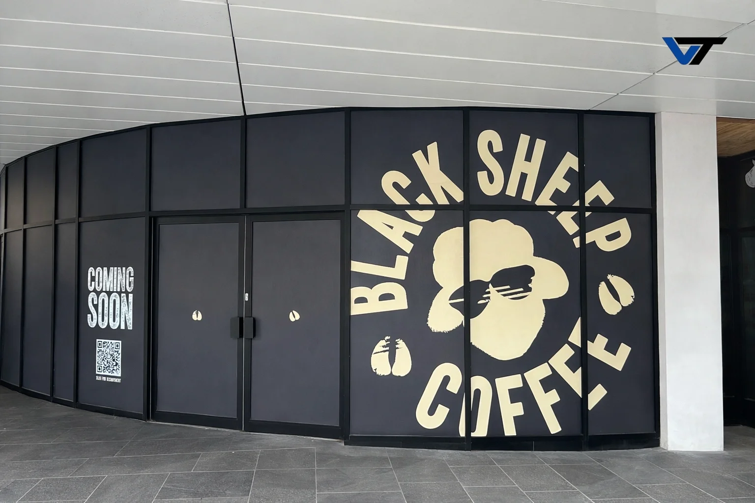 Storefront with black exterior and large sign that reads "Black Sheep Coffee" with a sheep graphic. Smaller text on the left says "Coming Soon" with a QR code.