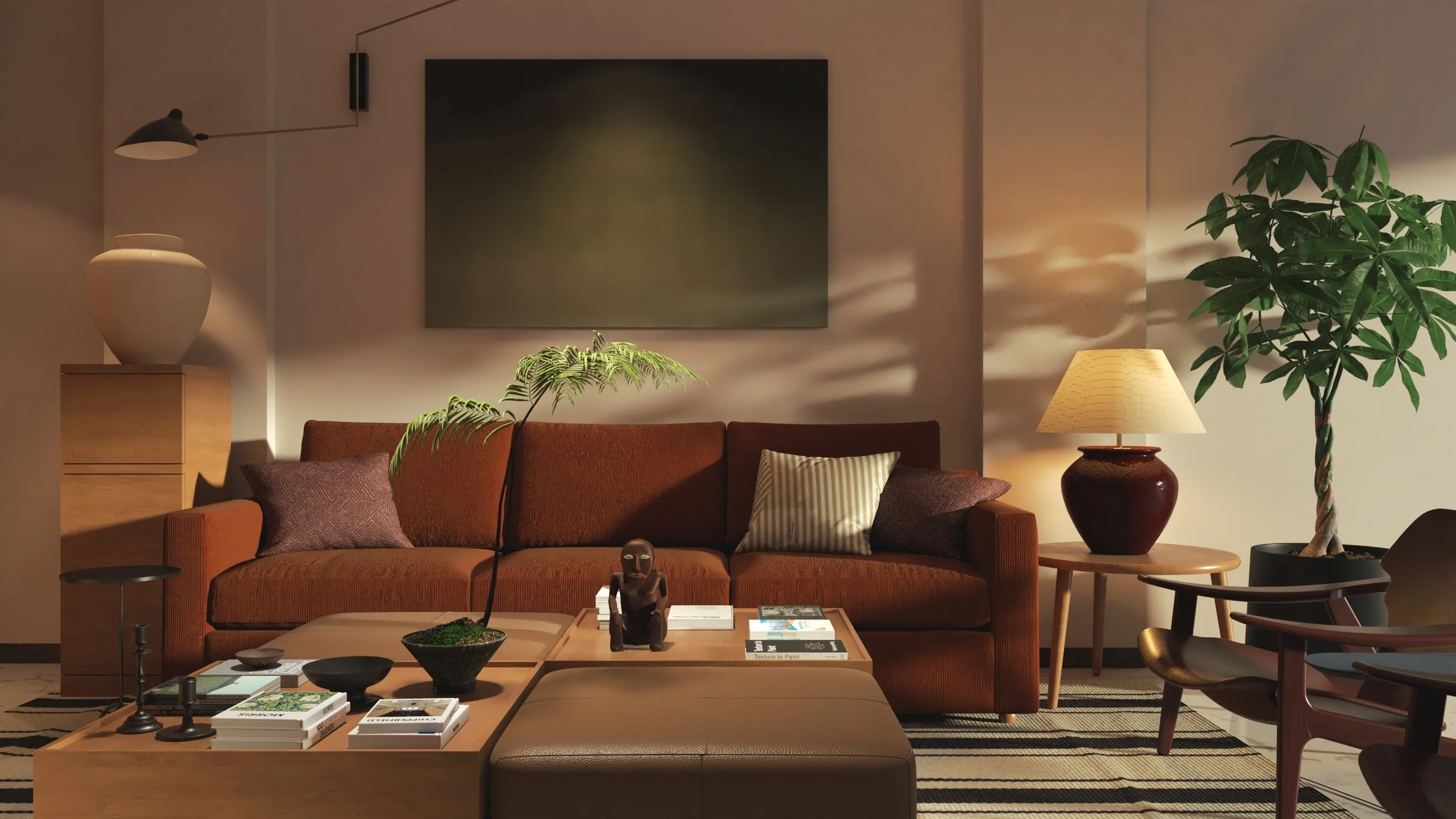 Living room with a brown sofa, side table with a lamp, large houseplant, abstract wall art, and a coffee table with books and decorative items.