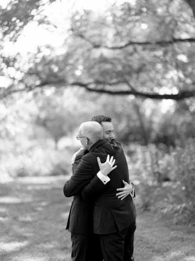 Two men hugging outdoors in a park.