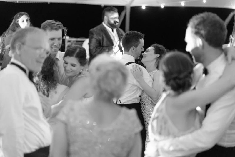 Couples and guests dancing at a wedding reception under a tent