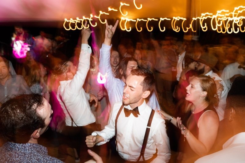 People dancing and enjoying a lively party with colorful lights and motion blur.