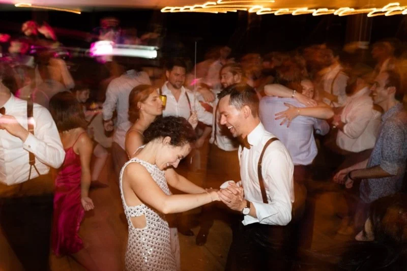 People dancing and socializing at a party or dance event in a dimly lit room.