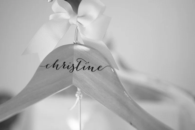 Personalized wooden hanger with the name 'Christina' written in black cursive, decorated with a white ribbon bow.