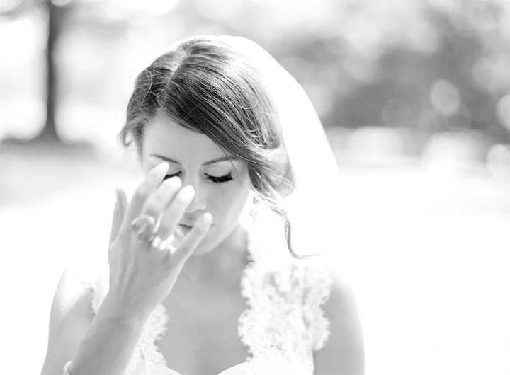 Black-and-white photo of a woman with her hand near her face, appearing emotional or distressed.