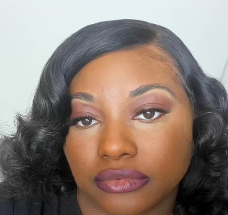 Close-up of a woman with dark, curly hair and makeup, looking directly at the camera.