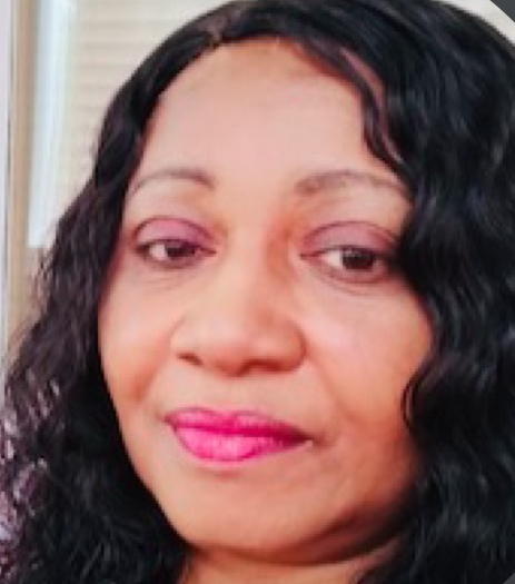 Close-up of a woman's face with curly black hair, pink lipstick, and a slight smile.