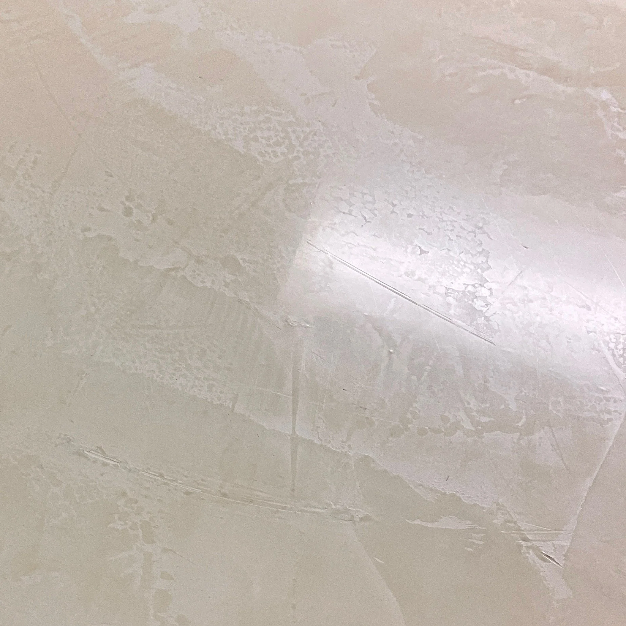 Close-up of a light-colored wall with textured paint and a subtle shadow