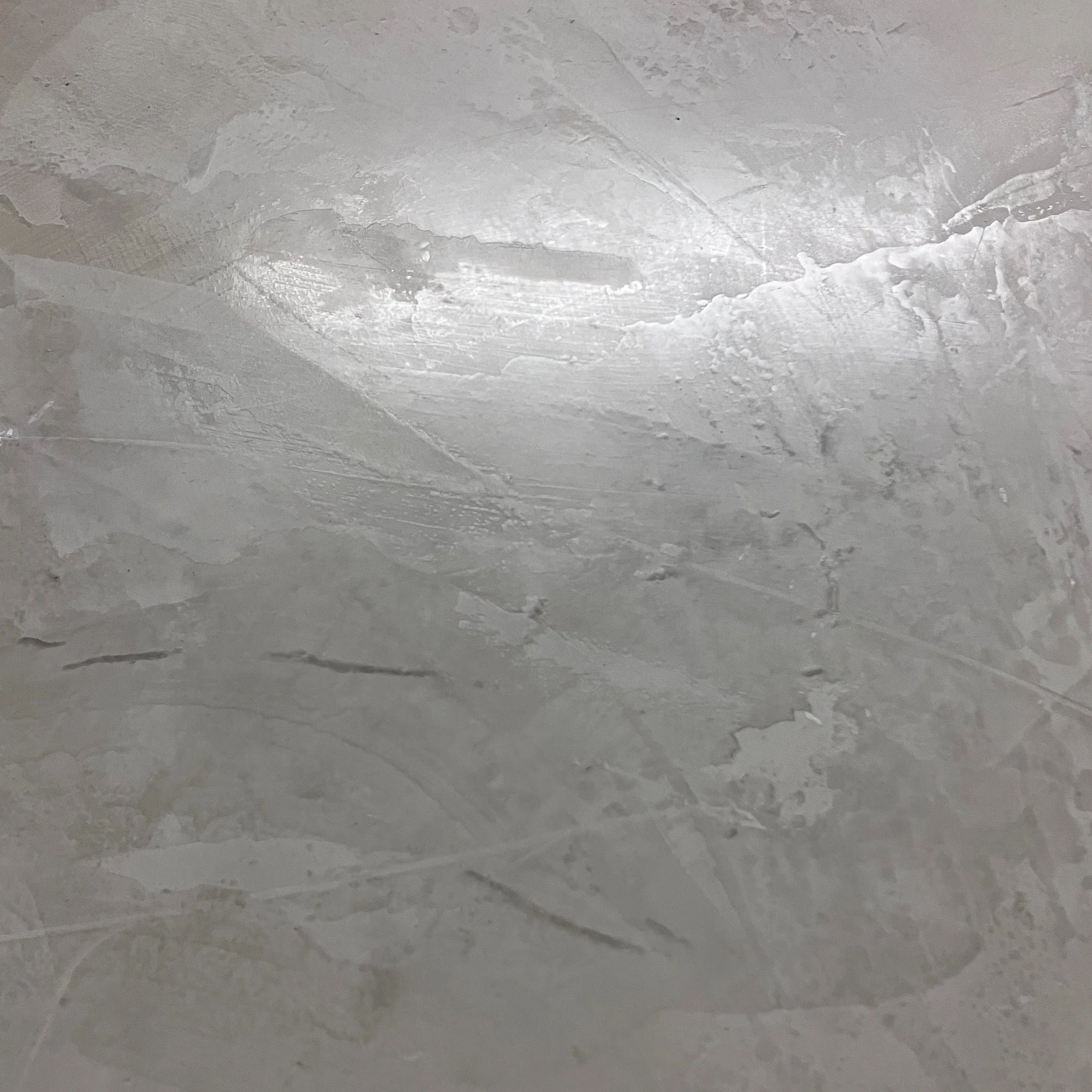 Close-up of a textured, painted wall or ceiling with visible brushstrokes and uneven surface.