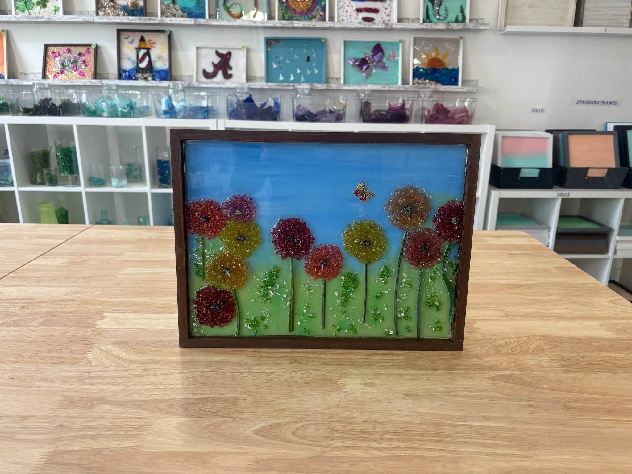 Resin Art of flowers using cut and crushed glass placed in a painted frame.