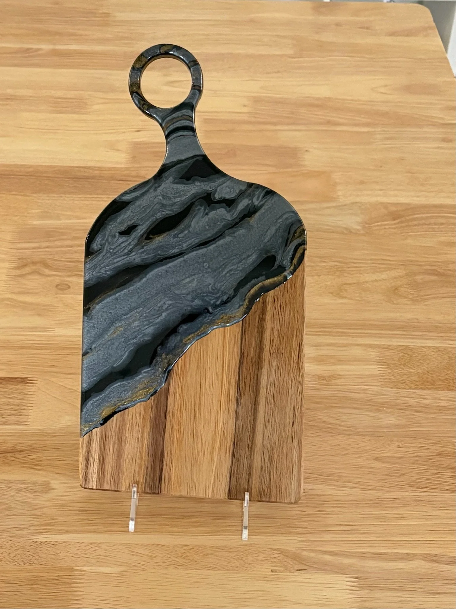 Wooden charcuterie board with resin poured on it using non-traditional colors in geode fashion.
