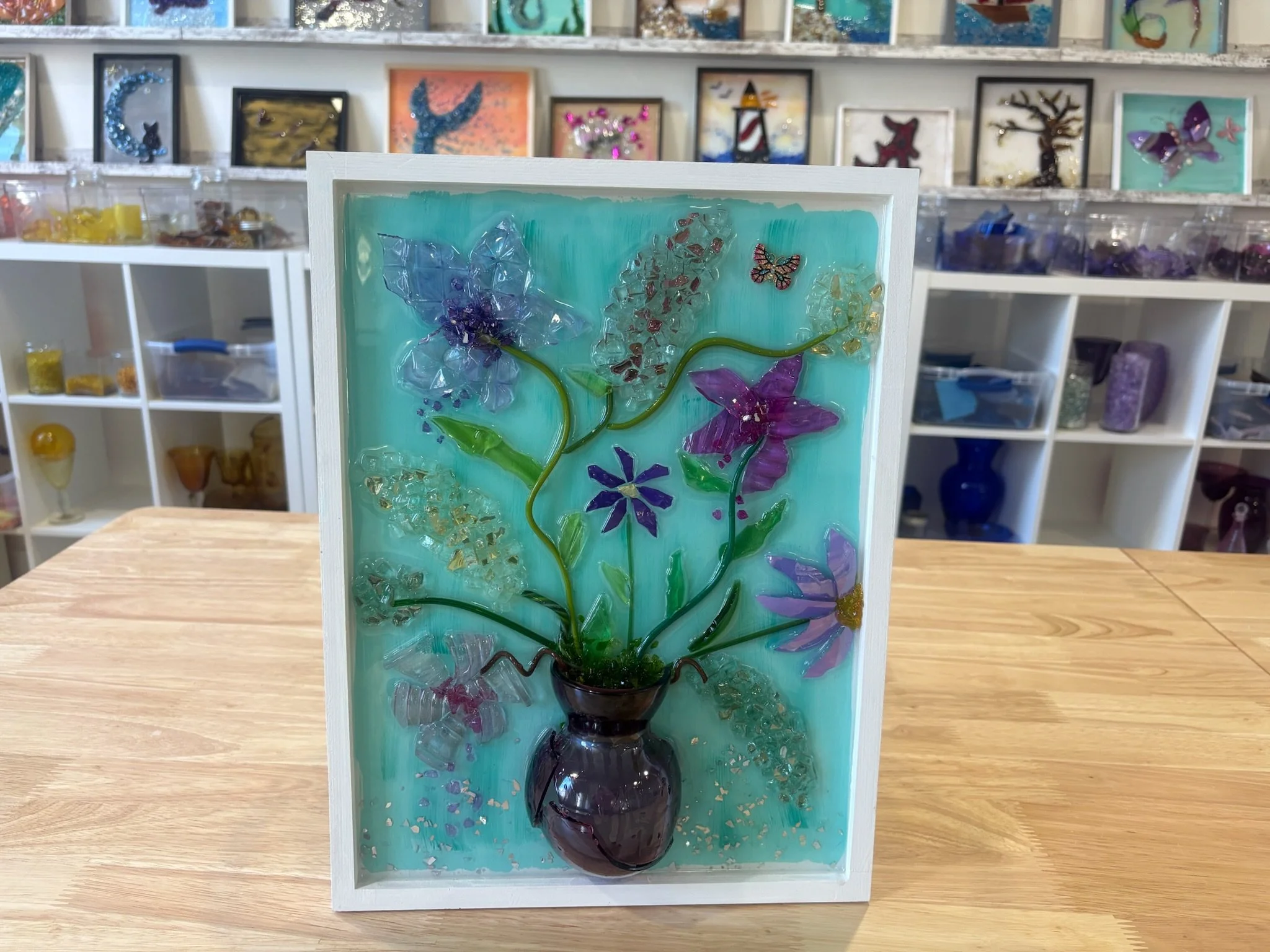 Resin Glass Art of an flowers in a vase using cut and crushed glass in a painted frame.