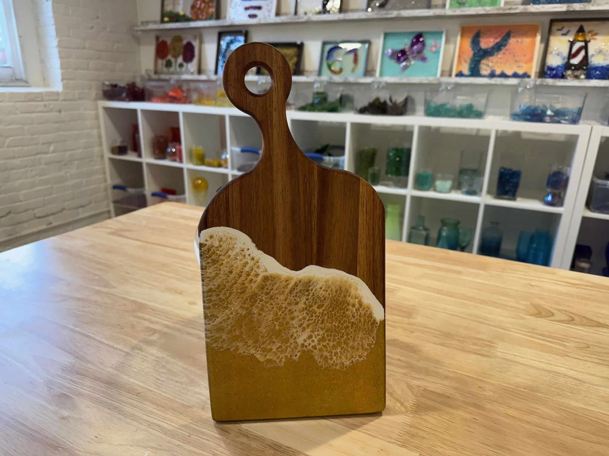Wooden charcuterie board with resin ocean wave using non-traditional colors.