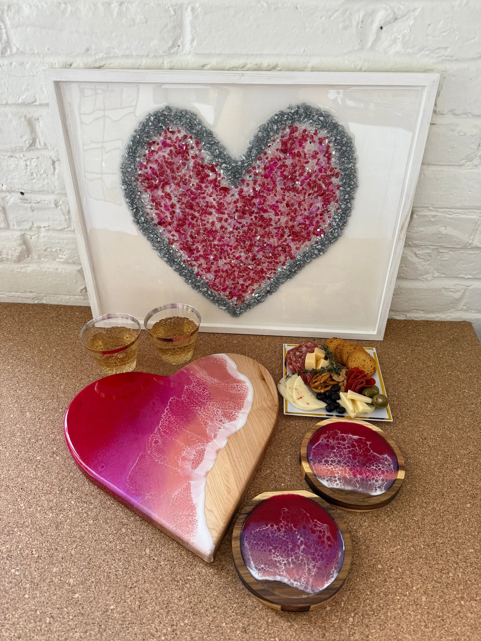 Valentine heart shaped charcuterie resin board, resin poured wood coasters in front of Glass Resin Heart