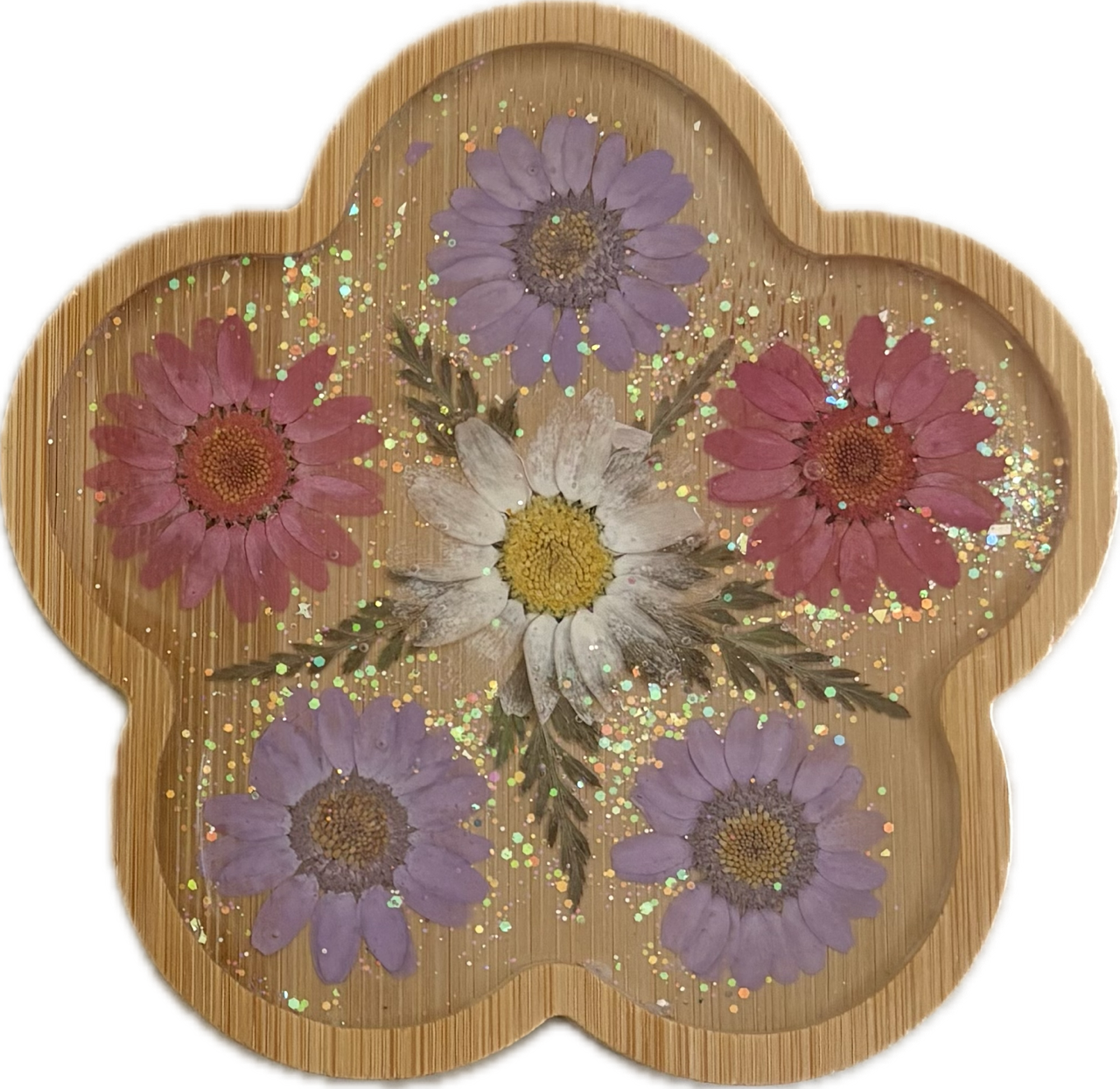 Resin flower wooden coaster. A wooden flower-shaped tray with six pressed flowers in purple, pink, white, and yellow, accented with scattered glitter.