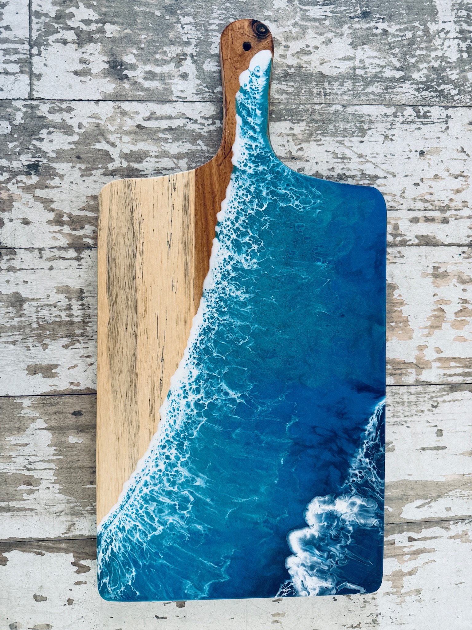 Wooden charcuterie board with resin ocean wave poured on it. 