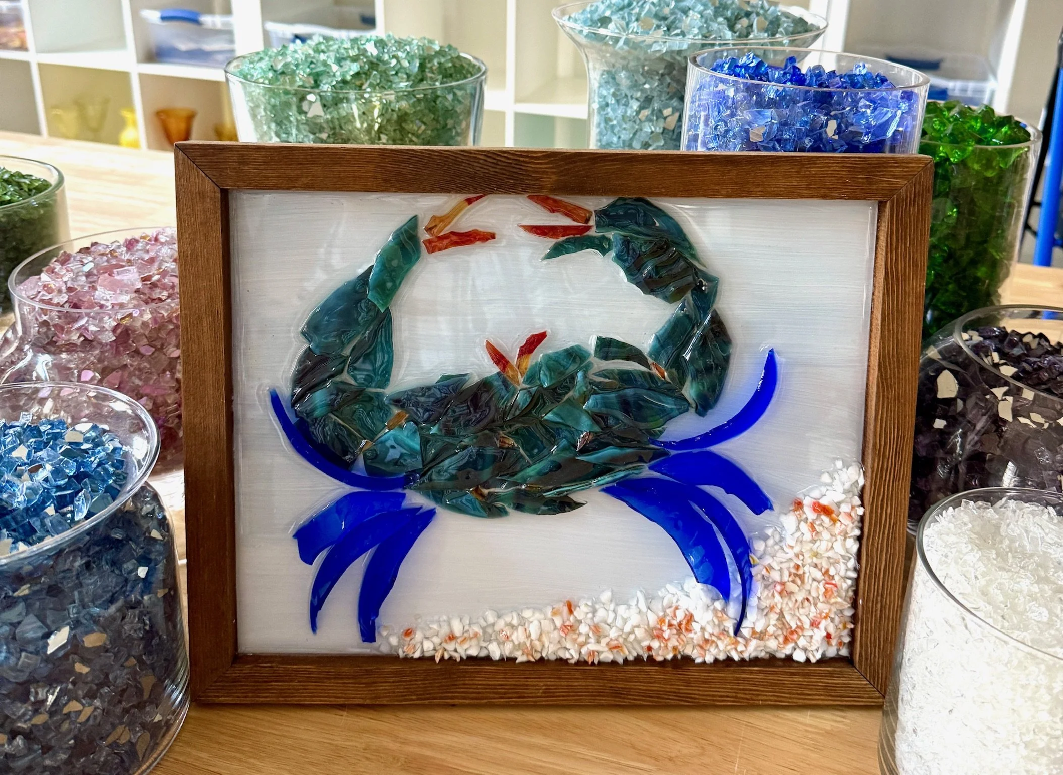 Resin Glass Art of a crab on the ocean floor using cut and crushed glass in a painted frame.