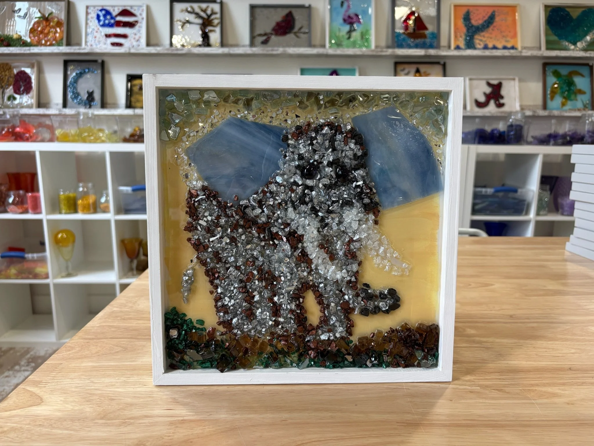 Resin Art of an elephant using cut and crushed glass placed in a painted frame.