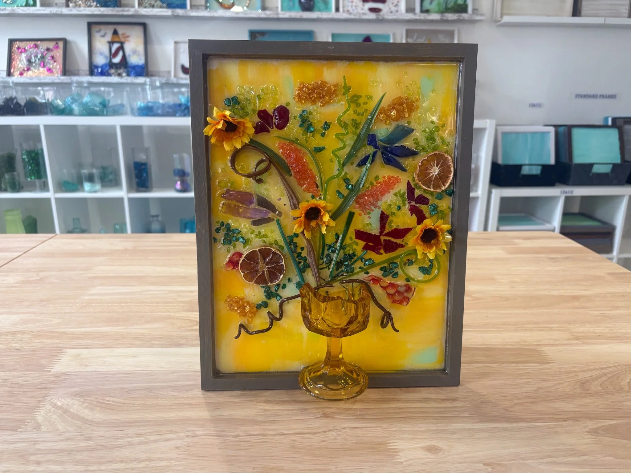 Resin Glass Art of flowers using cut and crushed glass in a painted frame.
