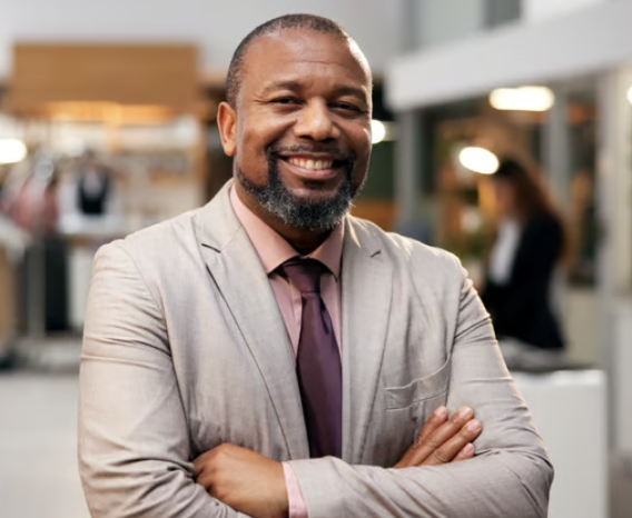 Smiling man in a suit with crossed arms at a professional event or conference.
