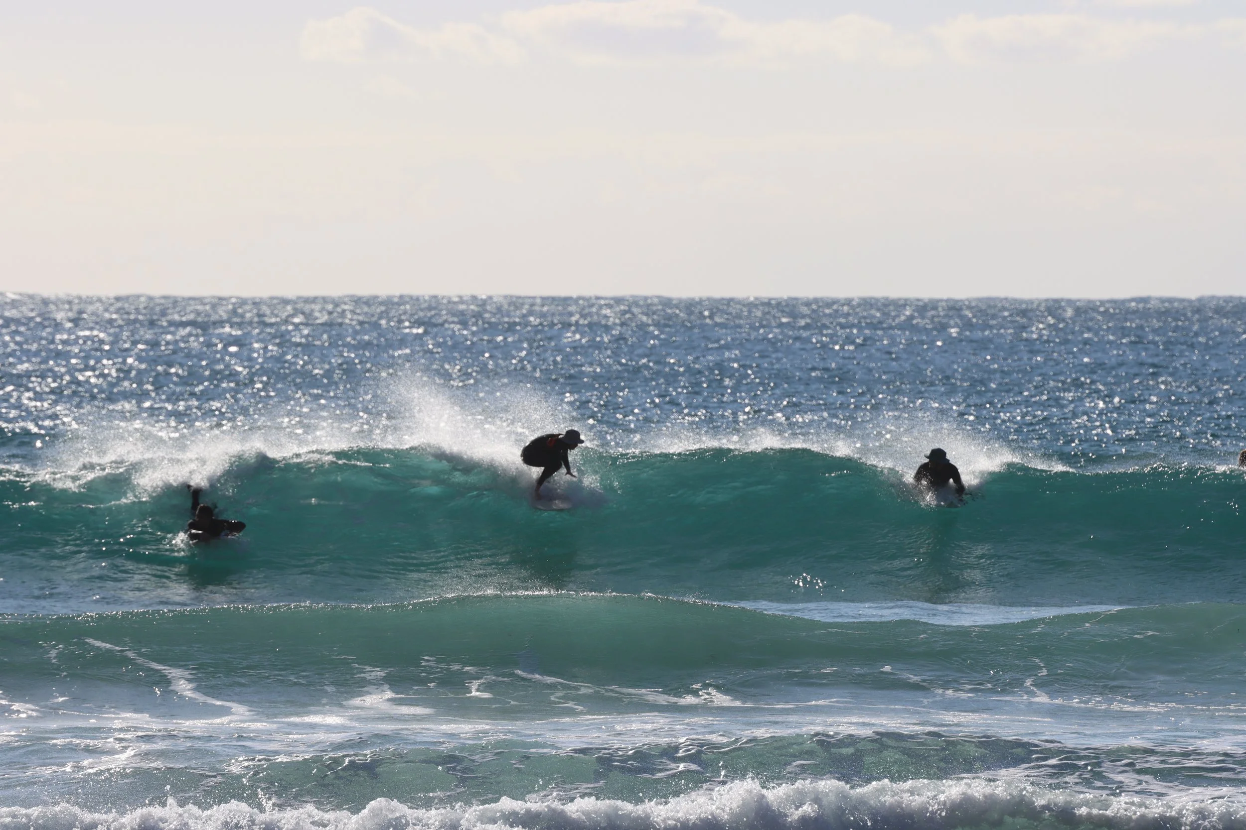 People surfing on the ocean waves with a clear sky in the background.