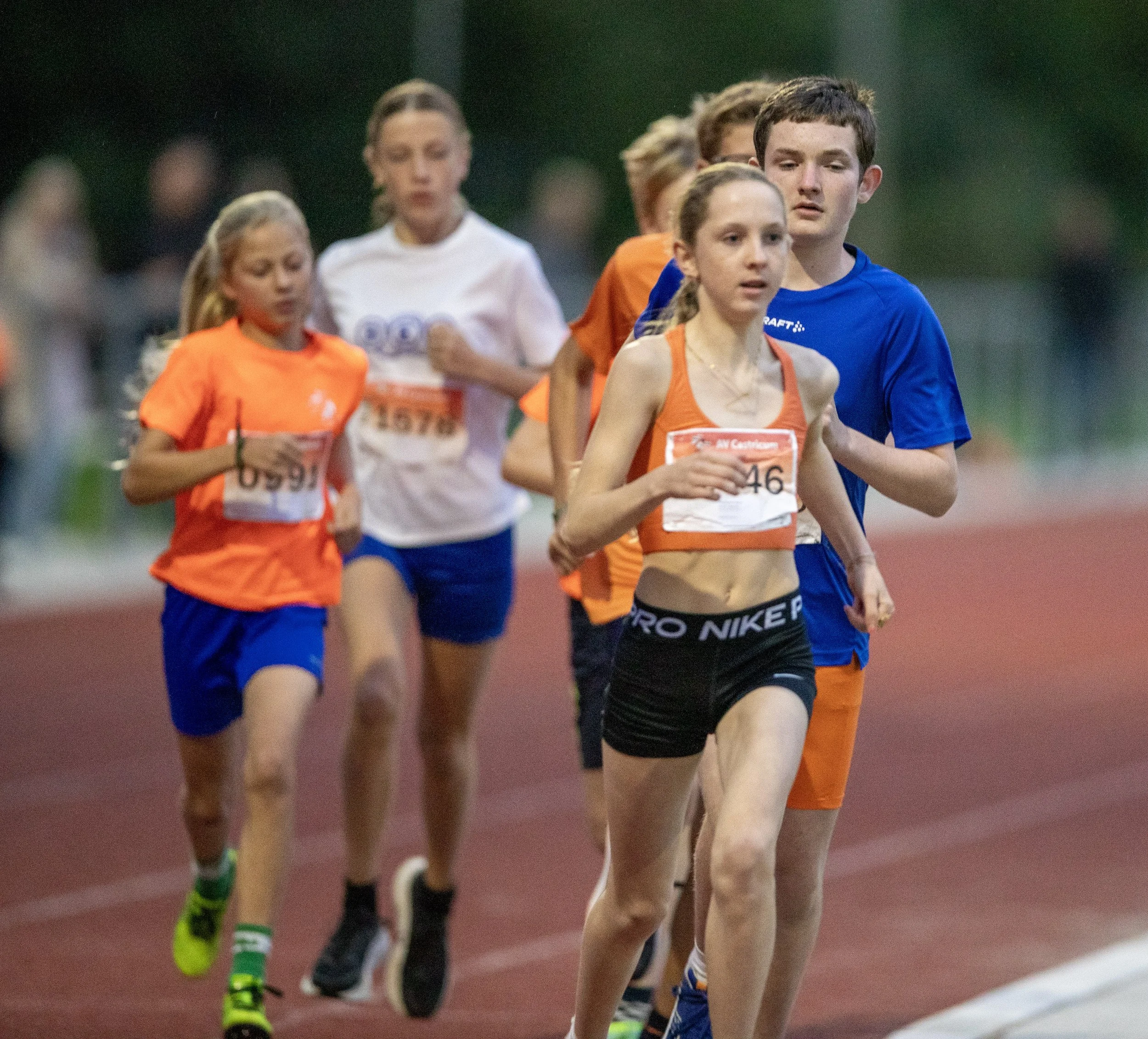 Children running in a race on a track, wearing colorful athletic clothing.