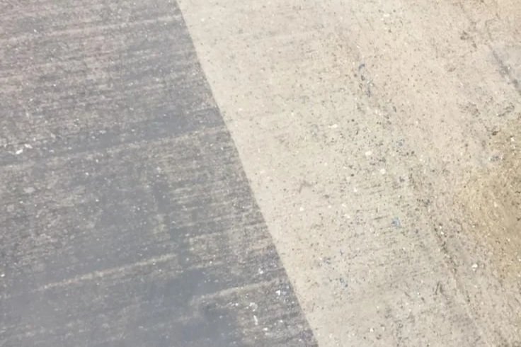 Close-up of concrete ground with a shadow cast across part of the surface.