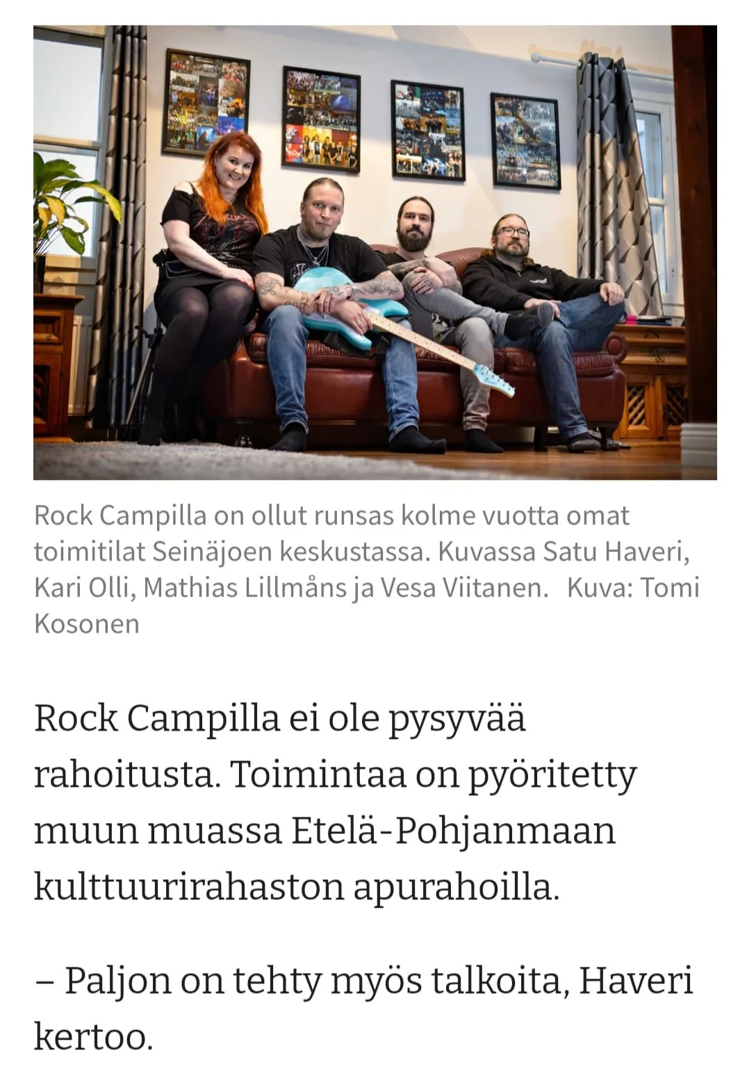 Neljän ihmisen ryhmä istuu sohvalla olohuoneessa, takana seinällä on neljä taulukkoa. Yksi ihmisistä pitää sinistä sähkökitaran ja muut istuvat vieressä. Vasemmalta oikealle: nainen ja kolme miestä.