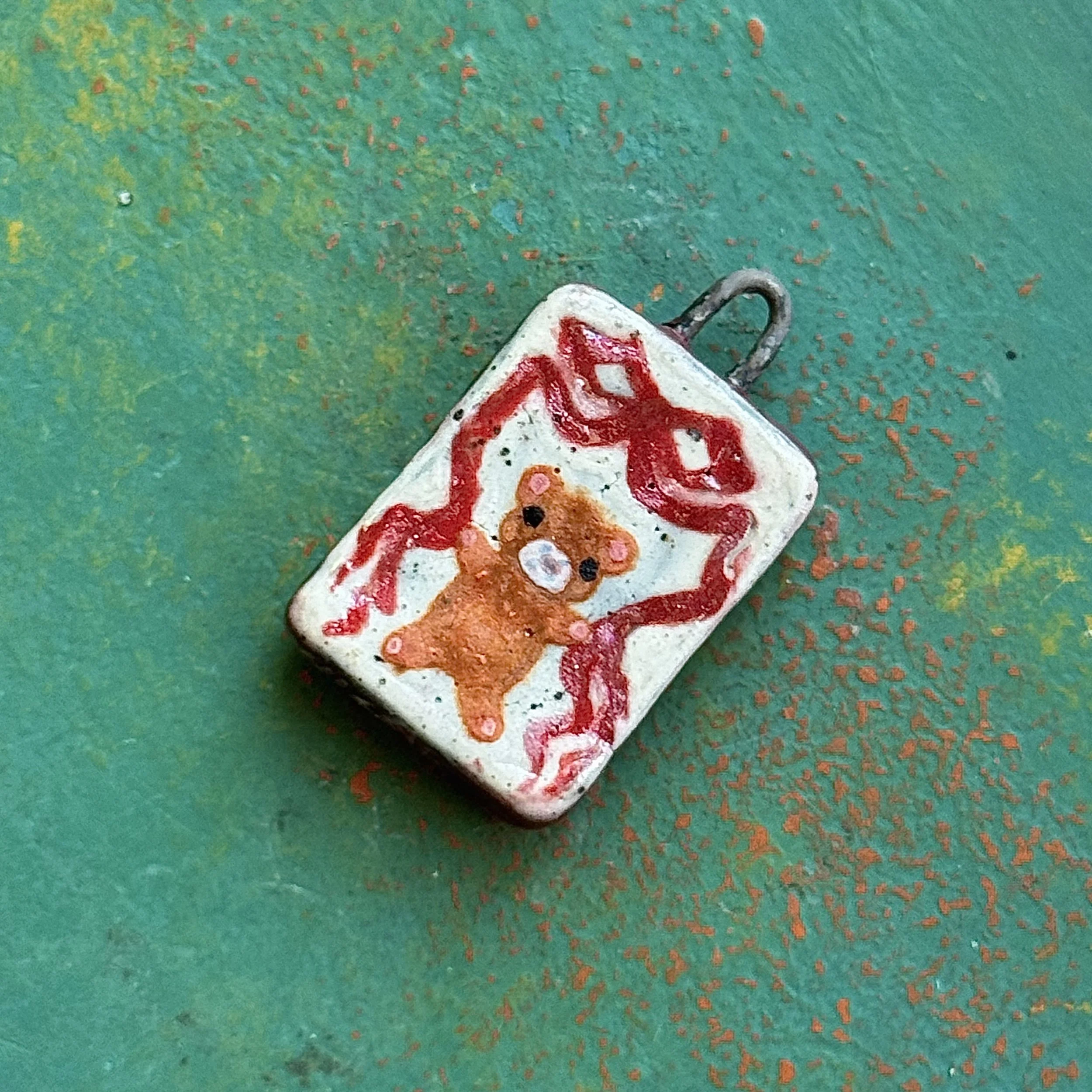 "DOLLS WILL BE DOLLS" (front), red earth ceramic pendant, velvet underglaze, white gold/mother of pearl lustre