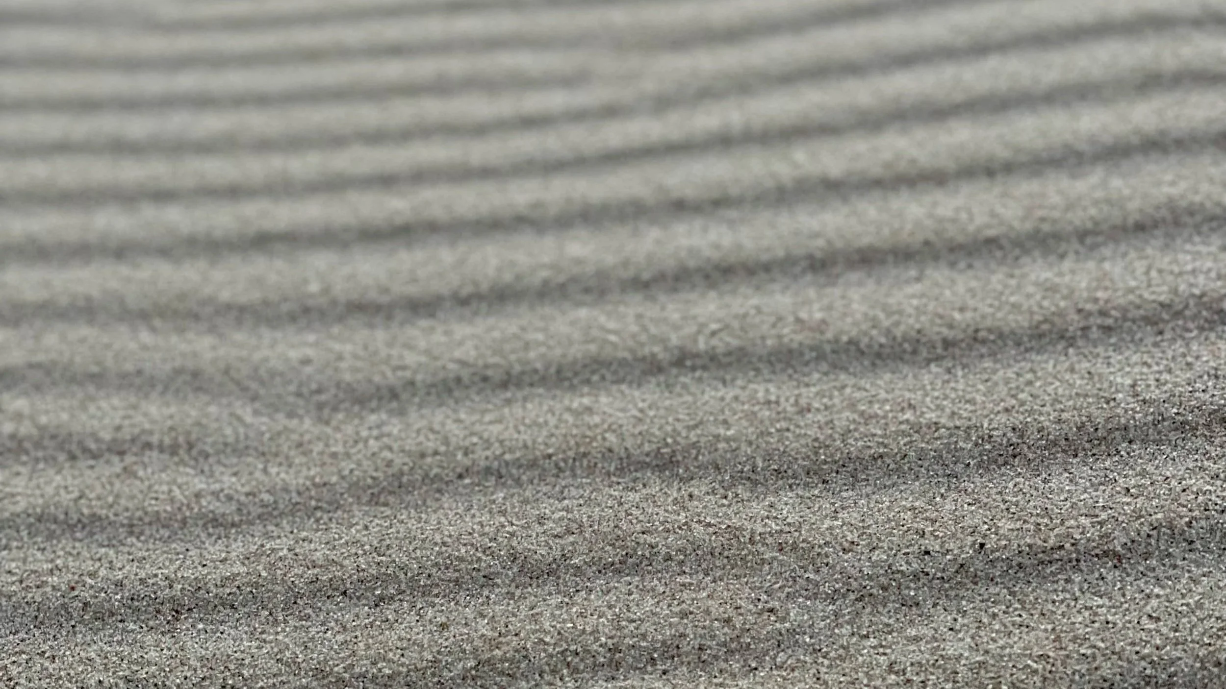 Close-up of sandy beach with parallel ridges in the sand.