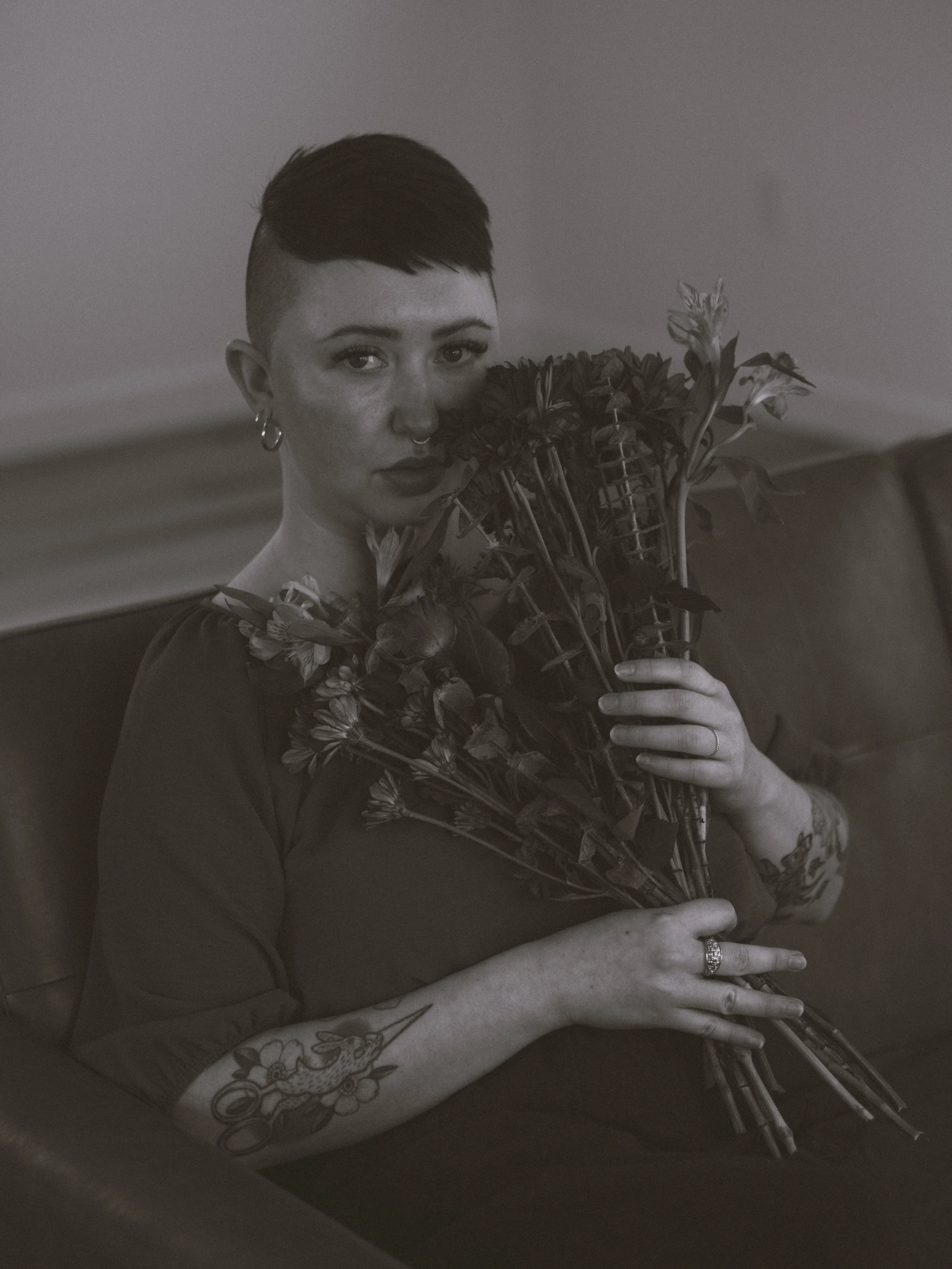 Black and white portrait of a queer, biracial femme person featuring a bouquet of flowers.