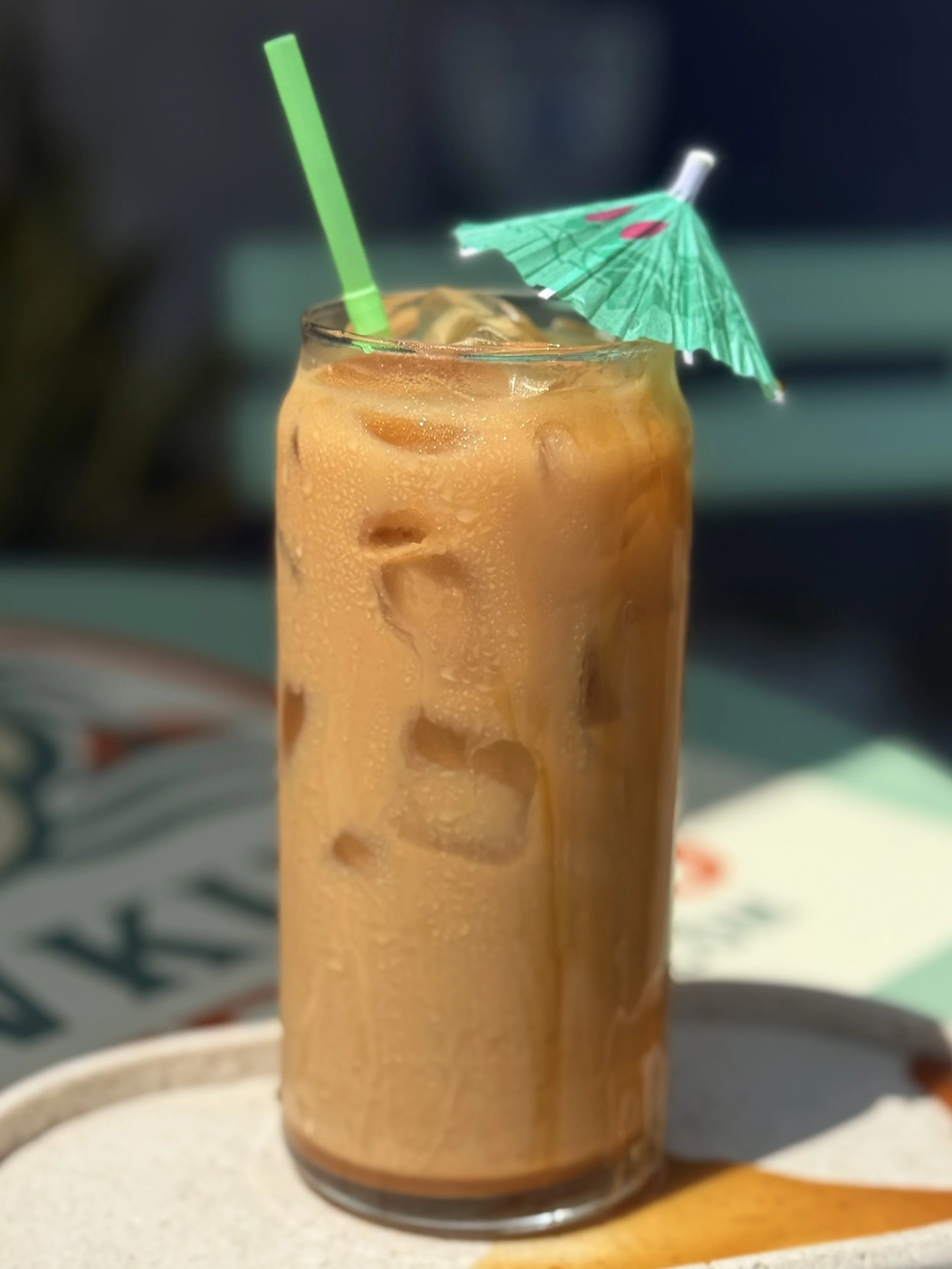a glass with an espresso, caramel, vanilla latte with a umbrella in it