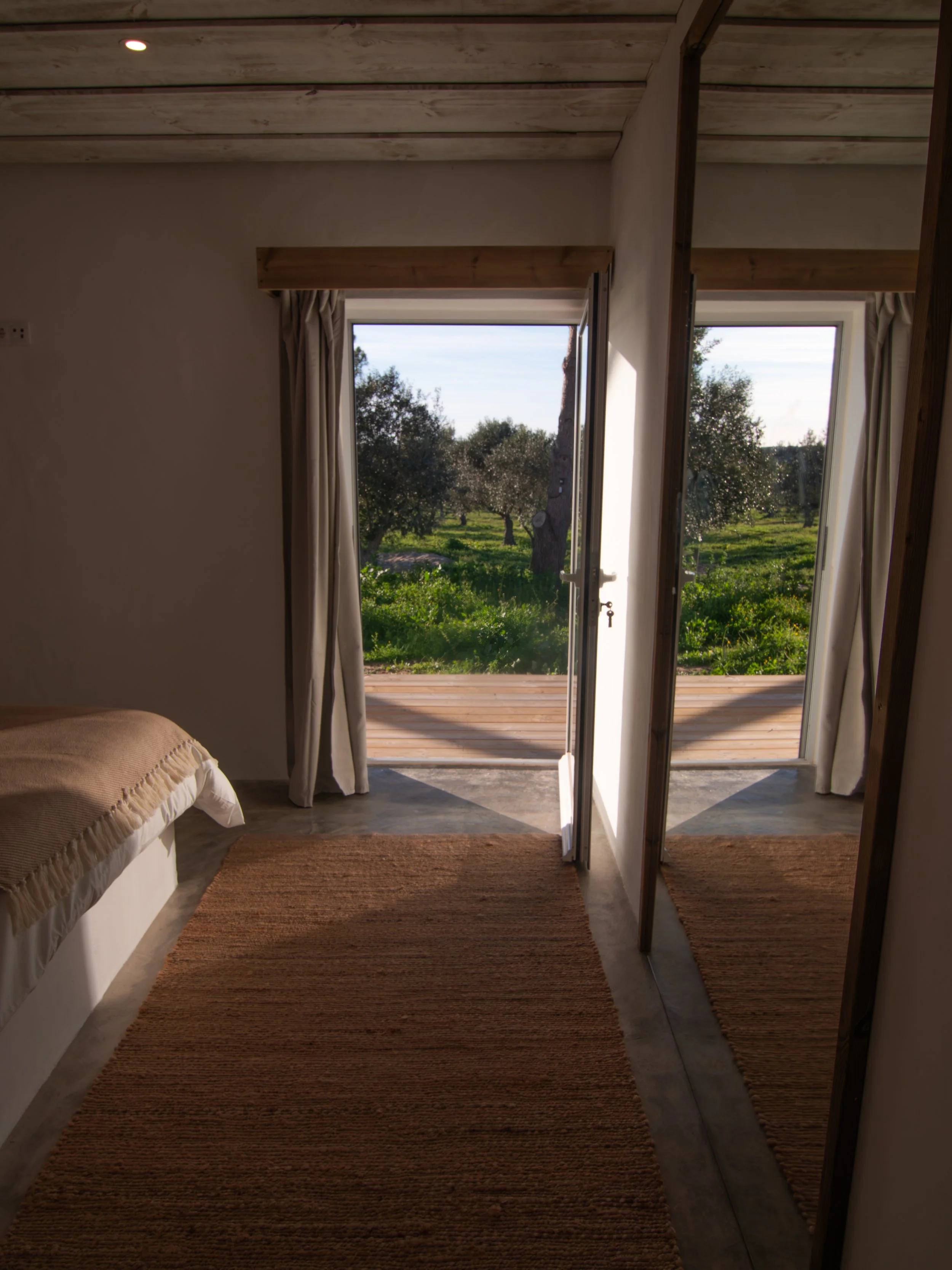 Looking out from inside Casa Thala through an open door onto the trees and grass of the farm.