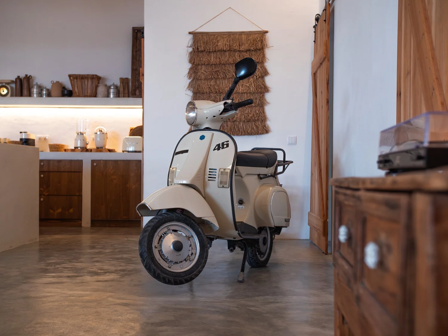 A cream vintage scooter parked in the rustic kitchen at Casa Thala.
