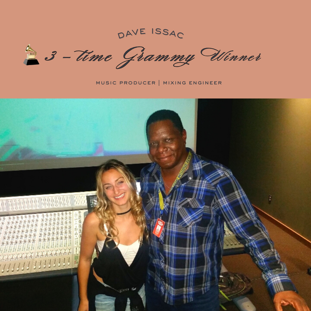 A young woman and a man standing together in a recording studio, smiling at the camera, with audio mixing equipment and a large screen behind them.