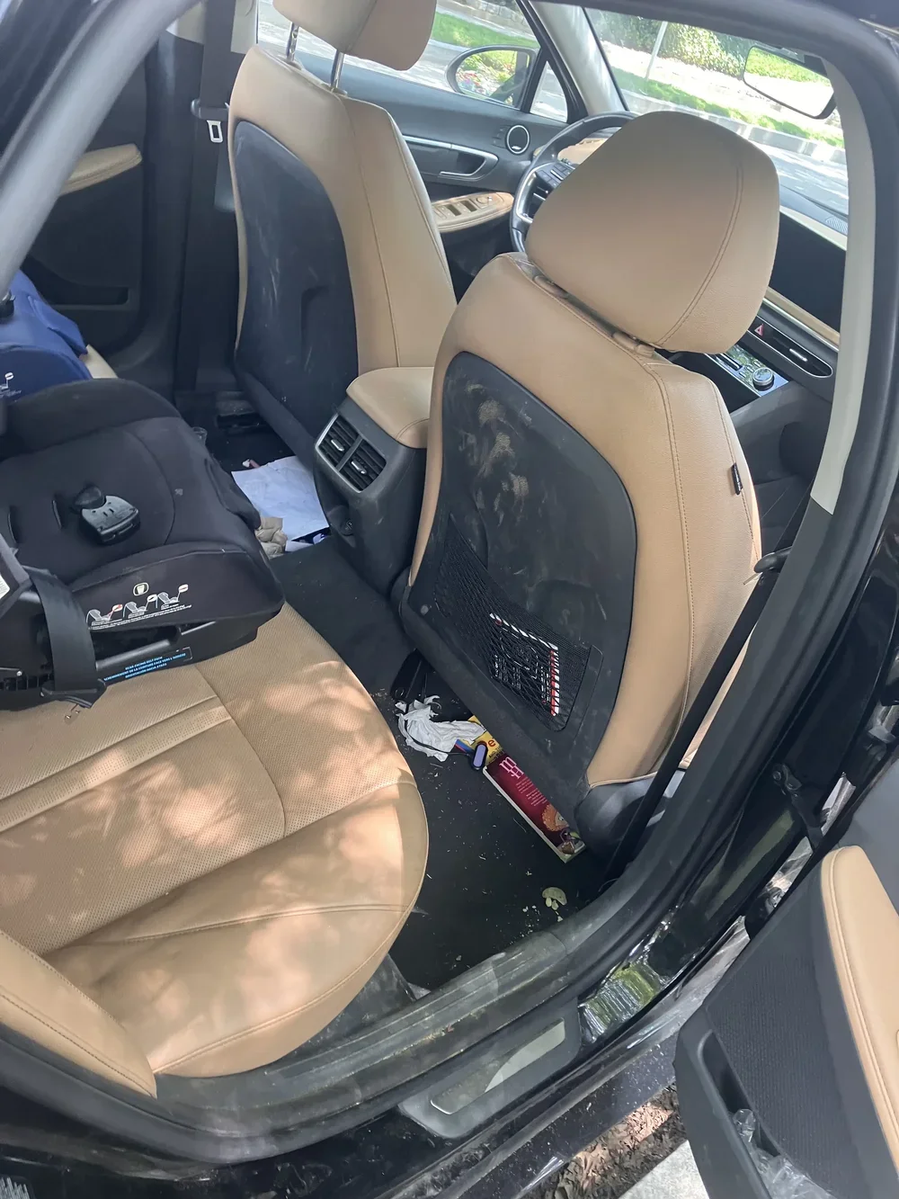 Tan leather car seats with dirt and crumbs before interior detailing in DC