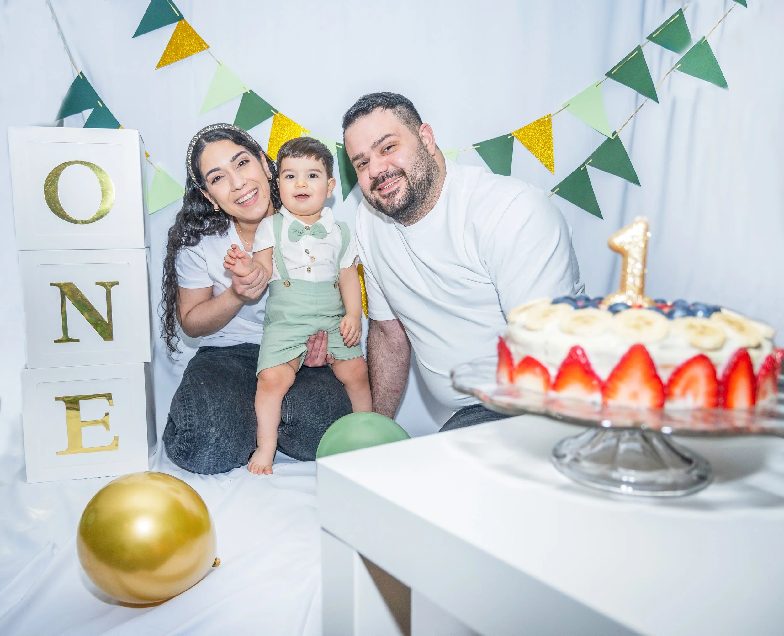 Family celebrating a birthday with a cake, balloons, and party decorations.