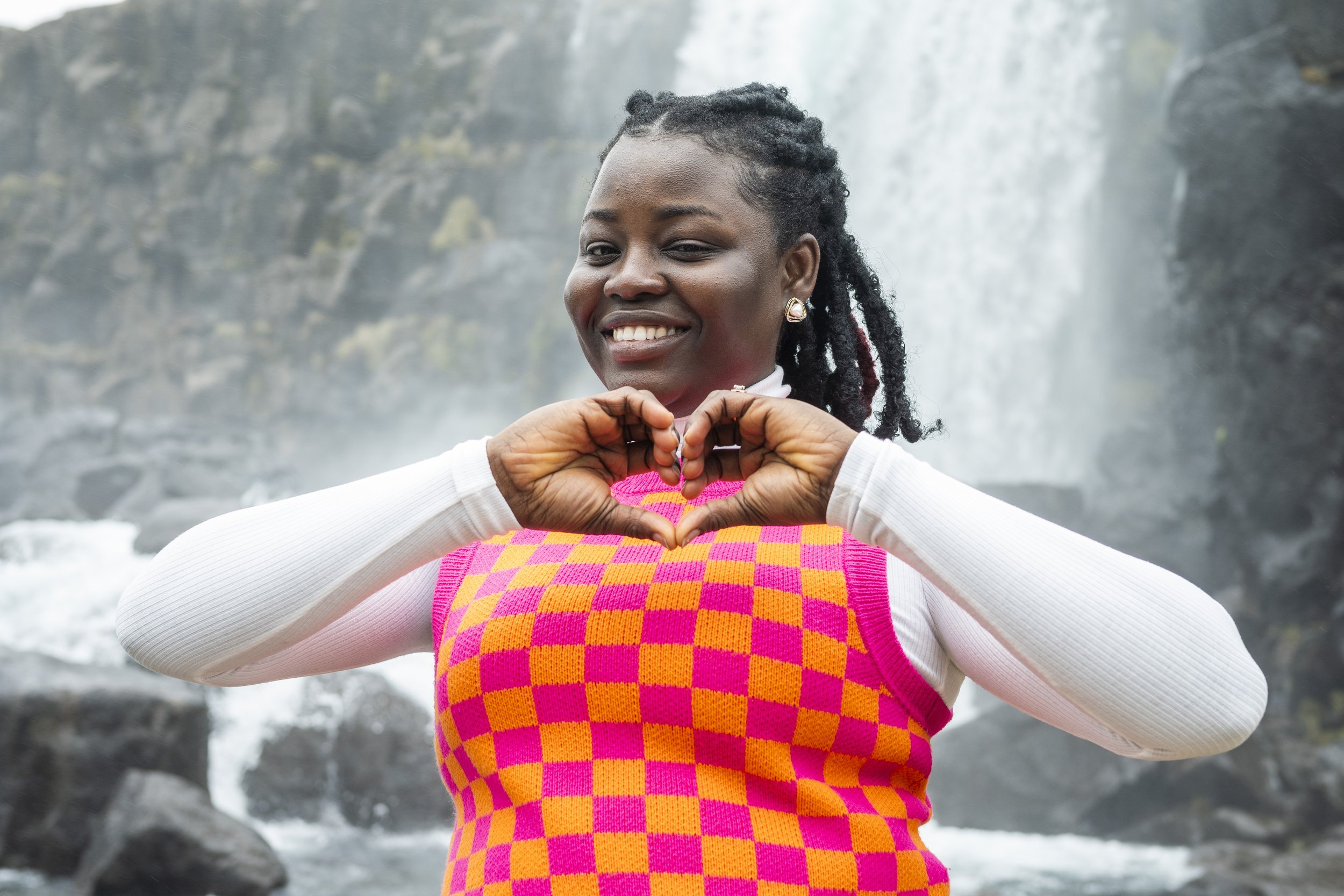 A woman smiling in front of a waterfall, making a heart shape with her hands.
Thingvellir National Park in Iceland
