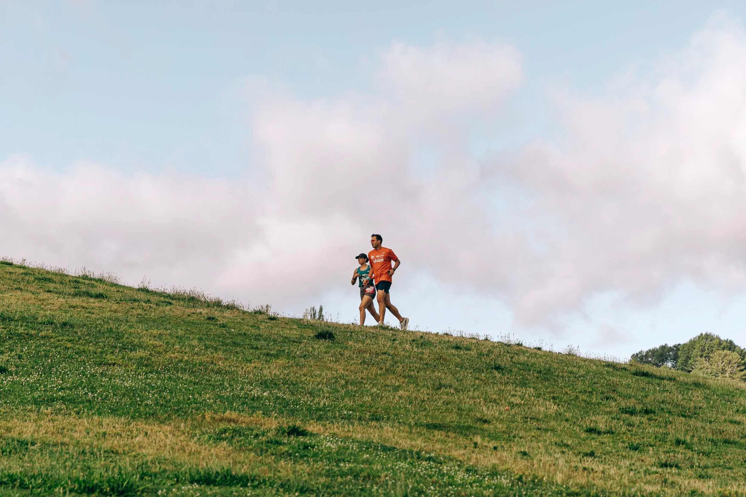 the photo shows two runners, a guide and a blind runner, using a tether and wearing free 2 fly shirts