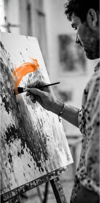 Homem pintando uma tela com tinta laranja em um estúdio de arte