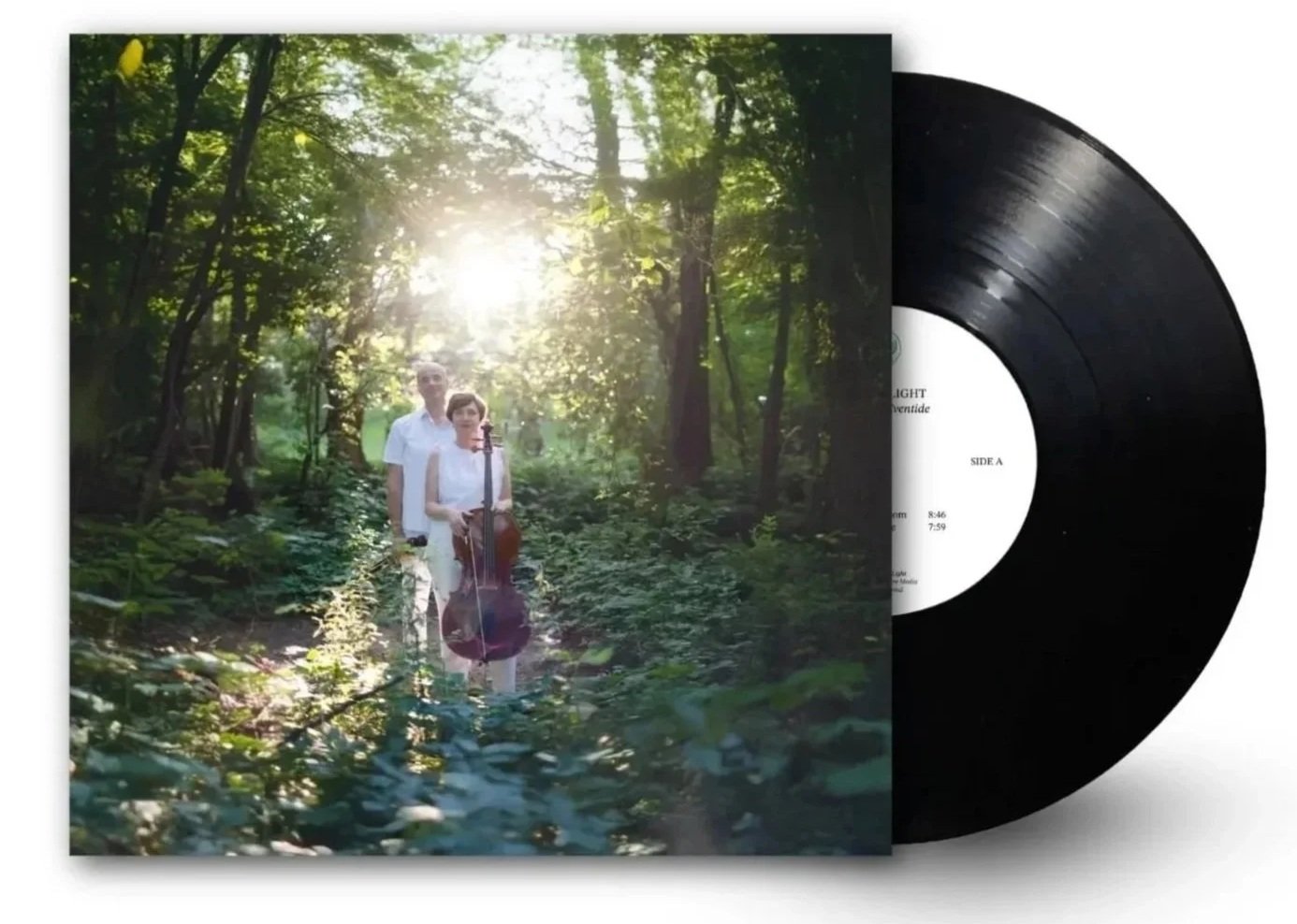 A vinyl record and album cover featuring two women and one man walking through a green forest with sunlight shining through the trees, carrying musical instruments.