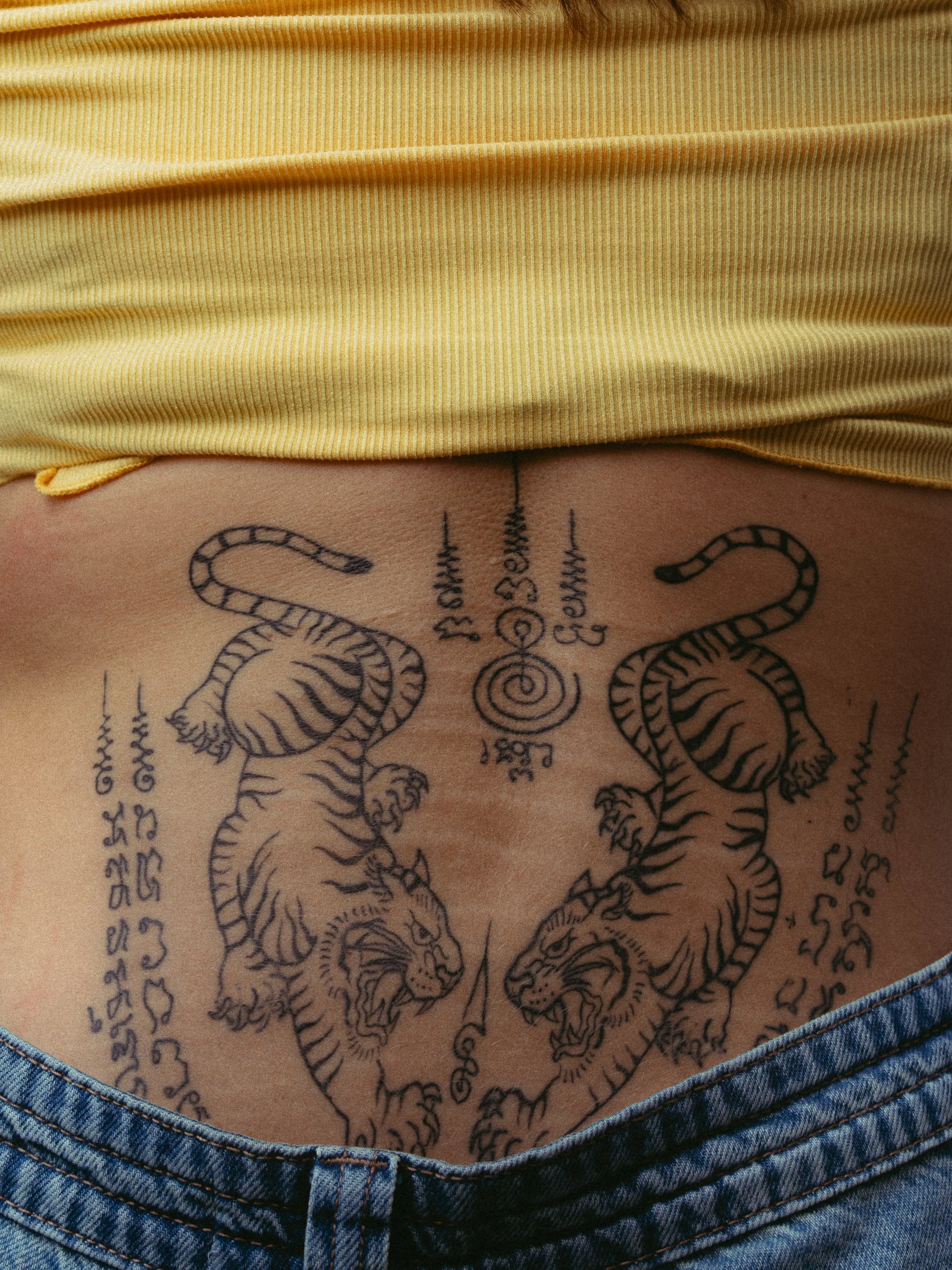 Tattoo of two roaring tigers with detailed stripes and whiskers on person's lower abdomen. Personal Branding Photography and Headshots in London.