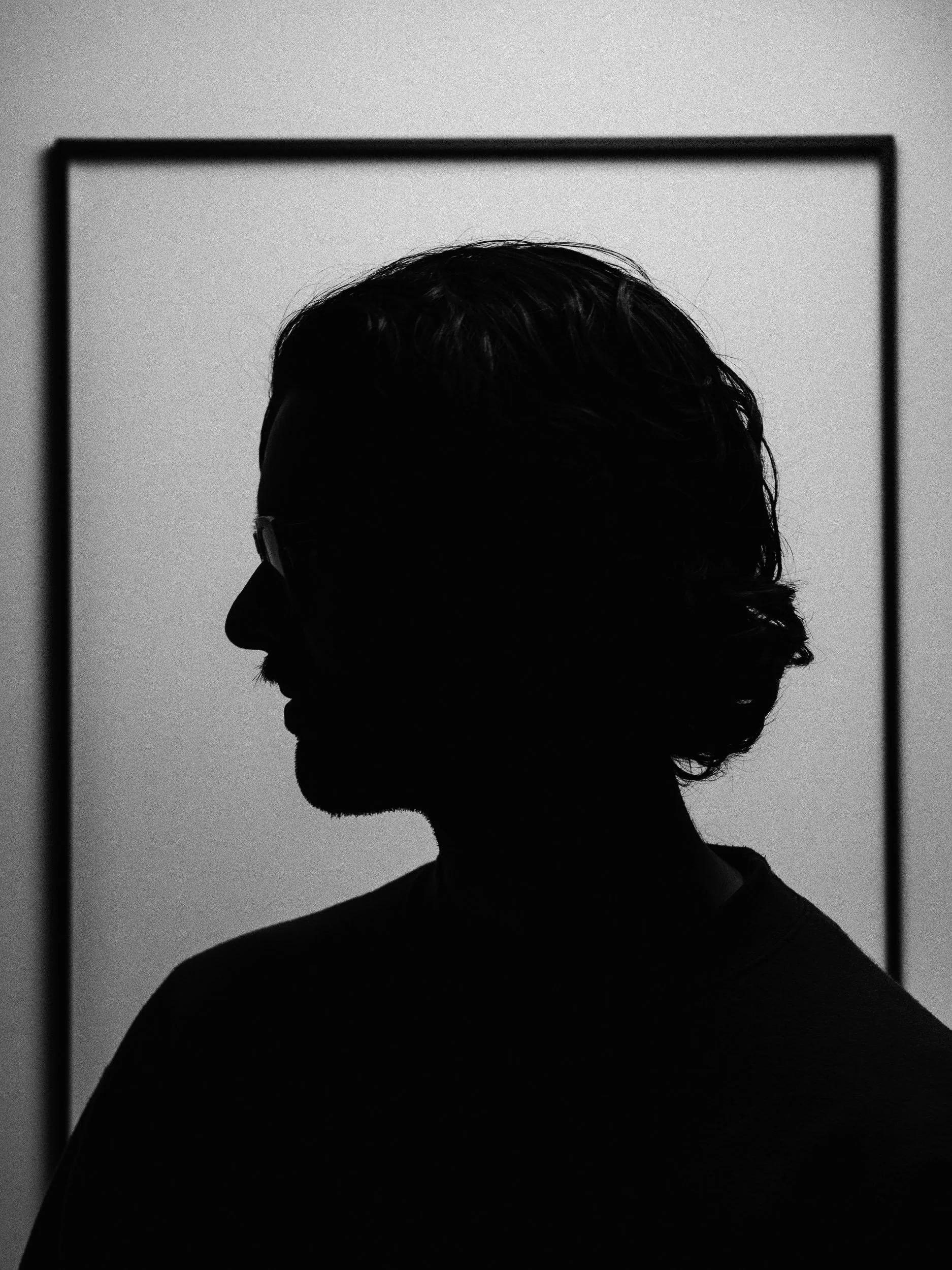 Silhouette of a man with glasses viewed in profile, with a rectangular frame around him, in black and white. Personal Branding Photography and Headshots in London.