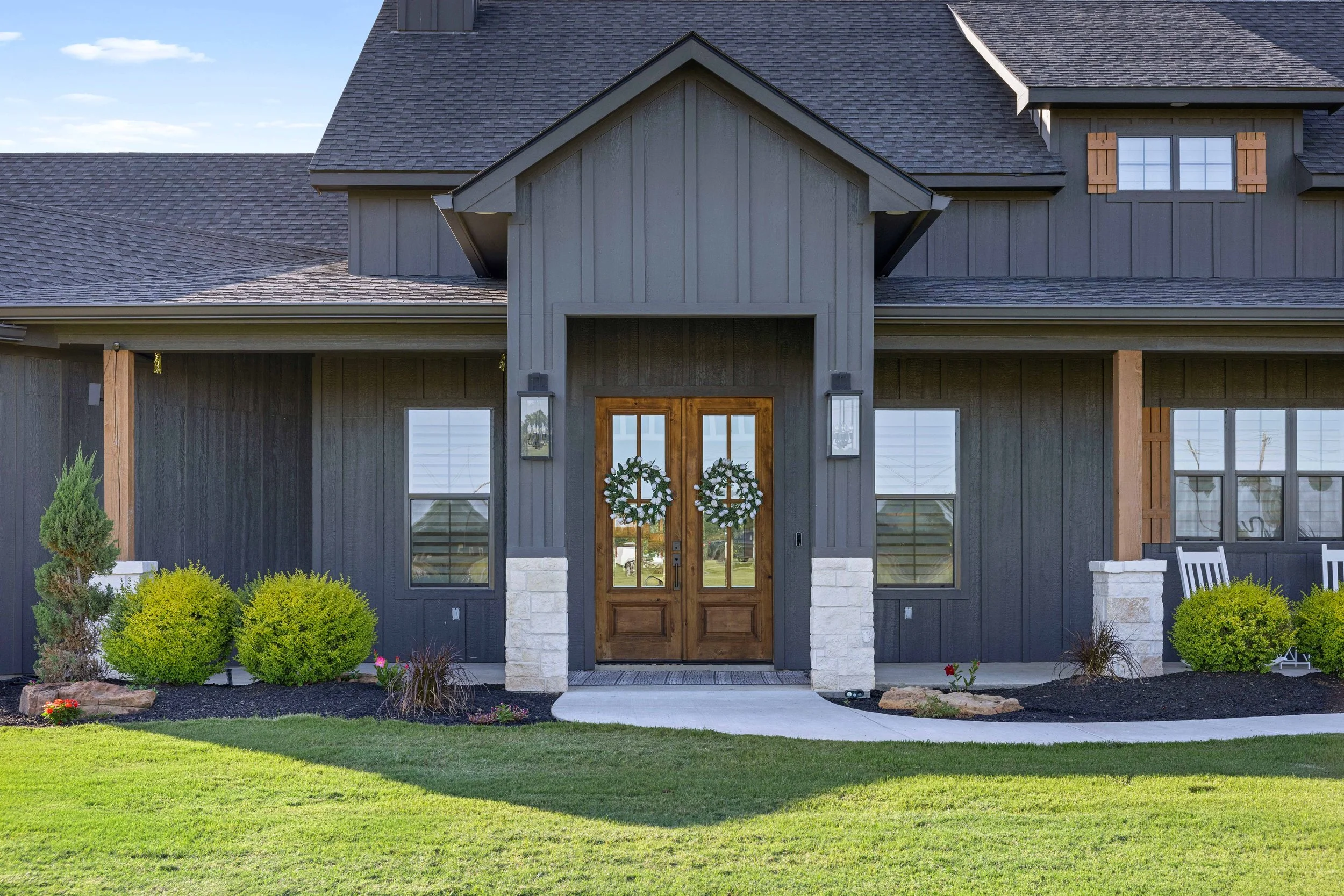 Skycrafted Imaging_Real Estate Media Production_Central & Southeast Texas_Front view of a modern house with gray wood siding, stone accents, and a dark shingle roof.