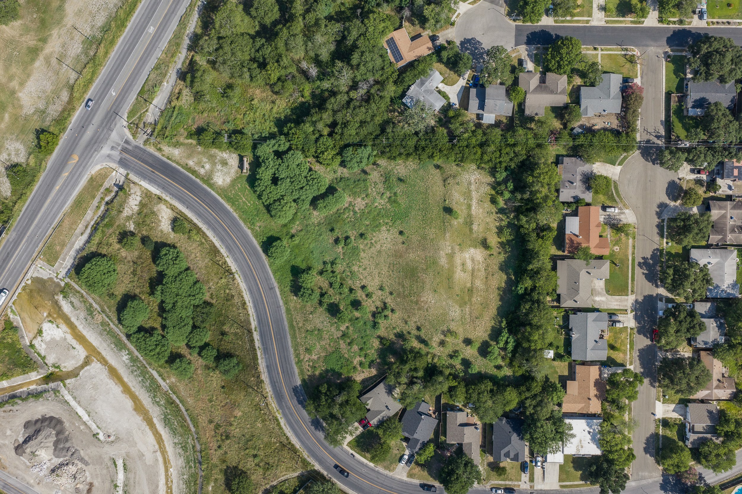 Skycrafted Imaging_Real Estate Media Production_Central & Southeast Texas_Aerial view of a suburban neighborhood with houses, trees, and a curved road.