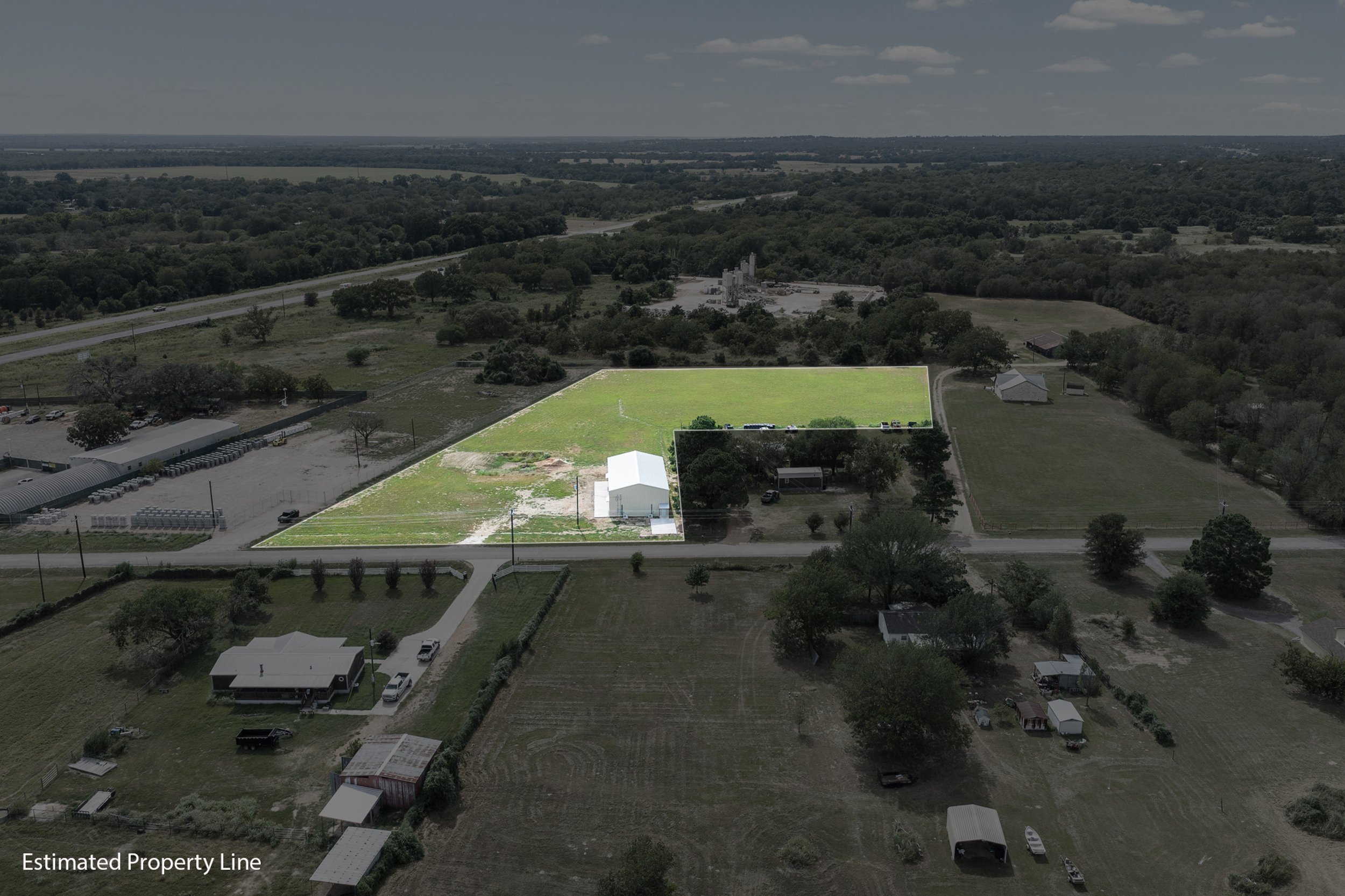Skycrafted Imaging_Real Estate Media Production_Central & Southeast Texas_Aerial view of a rural area with a green parcel of land outlined for an estimated property line, surrounded by trees.