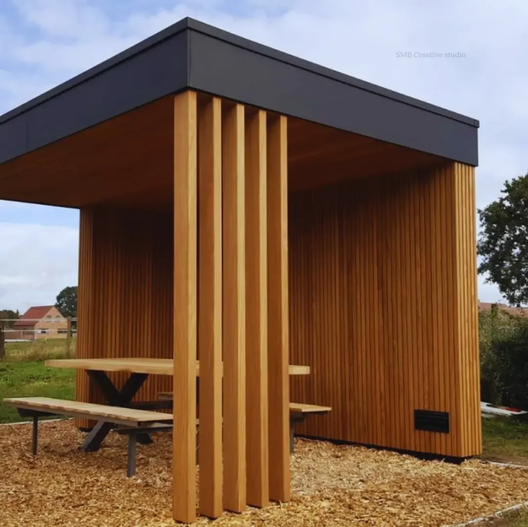 Modern wooden outdoor shelter with a black roof, vertical slats, and a picnic table underneath.