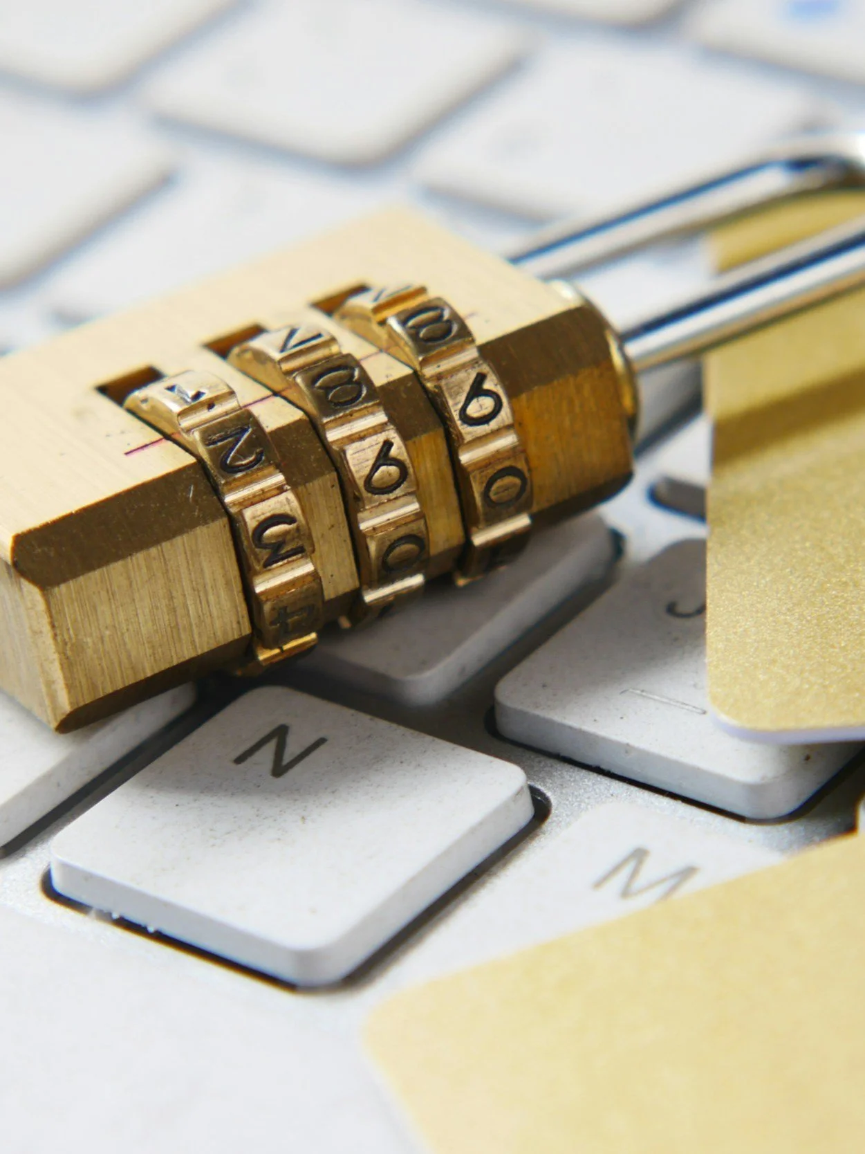 Close-up of a computer keyboard with a combination lock placed on the keys.